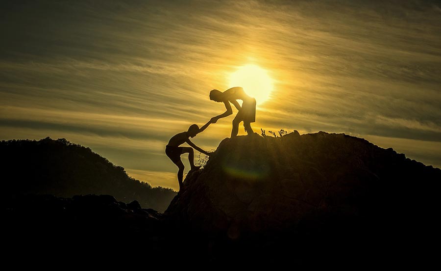 boys helping each other climb a hill